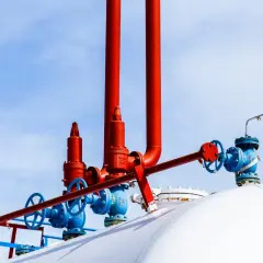 Czerwone i niebieskie zawory na białym zbiorniku na gaz. Zastanawiasz się, na ile wystarcza zbiornik na gaz 2700?