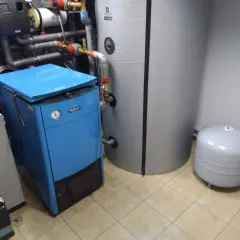 Jaki bufor do domu 150m2? W kotłowni stoi niebieski piec i duży zasobnik.