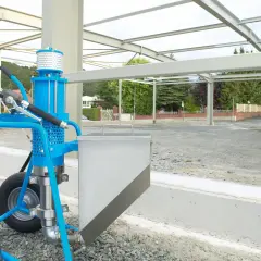 Niebieska pompa do betonu na placu budowy, gotowa do pracy przy konstrukcji stalowej.