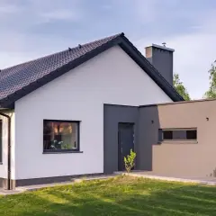 Nowoczesny dom z białymi i grafitowymi ścianami, prezentujący najmodniejsze kolory elewacji. Dachówka w ciemnym kolorze.