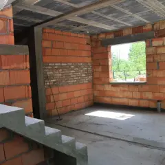 Trwa przekształcenie budynku gospodarczego na mieszkalny. Widoczne schody, ściany z pustaków ceramicznych i betonowy słup.