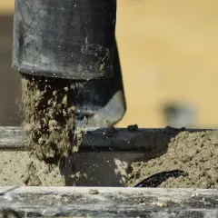 Beton wylewany z czarnej rury. Zastanawiasz się, ile schnie beton w temperaturze 5 stopni? Czekamy na odpowiedź.