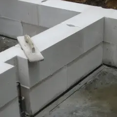 Ściana z bloczków z betonu komórkowego w trakcie budowy. Na jednym z bloczków leży kielnia.