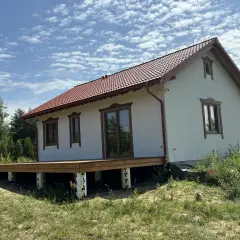 Nowy projekt domu drewnianego z tarasem, w otoczeniu zieleni.