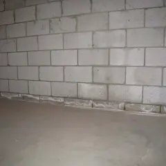 Ściana z bloczków betonowych, gdzie zaprawa murarska do bloczków betonowych tworzy solidne połączenie. Podłoga betonowa.