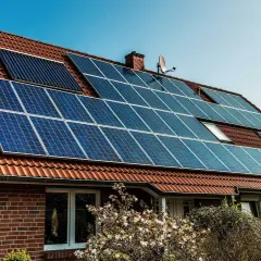 Dom z panelami fotowoltaicznymi na dachu. Instalacja fotowoltaika na starych zasadach, czerpiąca energię ze słońca.