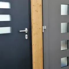 Dwa nowoczesne drzwi wejściowe, ciemnoszare i szare, z przeszkleniami. Dowiedz się, jak uszczelnić drzwi wejściowe, by chronić dom.