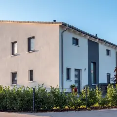 Nowoczesny dom z białym tynkiem i szarymi akcentami. Charakterystyczny dach jednospadowy konstrukcja.