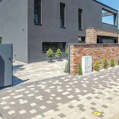 Nowoczesny dom z ceglanym murem i bramą. Podjazd i chodnik wykonane z kostki brukowej rodzaje w geometryczny wzór.