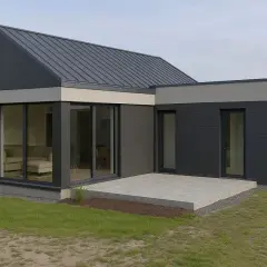 Nowoczesny dom z dużymi przeszkleniami, idealny do rozbudowy na zgłoszenie. Elegancka, ciemnoszara elewacja i betonowy taras.