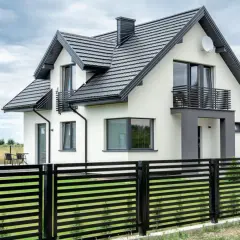 Nowoczesny dom z białymi ścianami i czarnym dachem. Eleganckie wykończenie ściany szczytowej podkreśla jego architekturę.