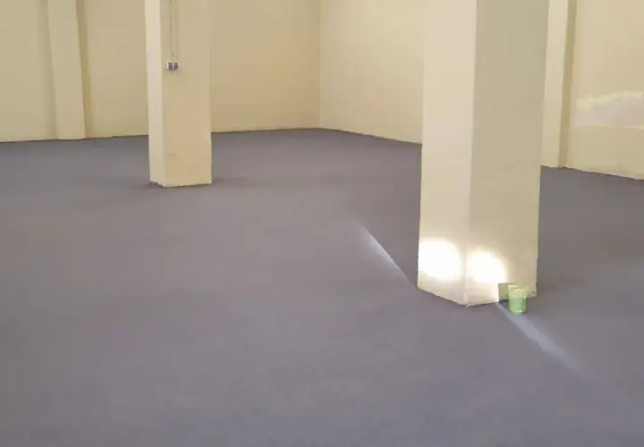 Nowa, szara posadzka betonowa w domu, z jasnymi filarami i żółtymi ścianami.