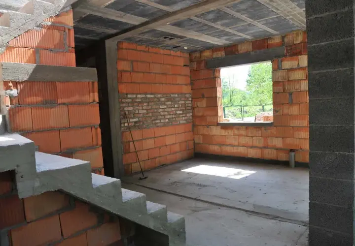 Trwa przekształcenie budynku gospodarczego na mieszkalny. Widoczne schody, ściany z pustaków ceramicznych i betonowy słup.