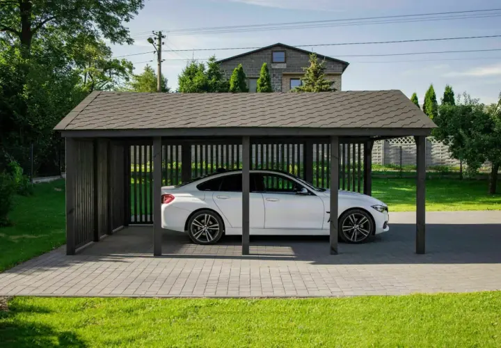 Białe auto pod ciemną, drewnianą wiatą bez zgłoszenia. Elegancka ochrona dla Twojego pojazdu.