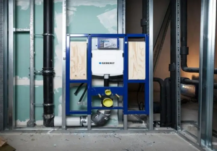 Montaż stelaża Geberit, widoczny podłączenie do odpływu. Instalacja hydrauliczna w trakcie budowy.