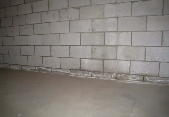 Ściana z bloczków betonowych, gdzie zaprawa murarska do bloczków betonowych tworzy solidne połączenie. Podłoga betonowa.