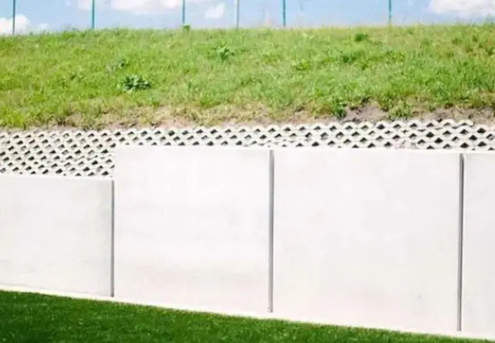 Solidny mur oporowy z betonowych płyt, nad nim ażurowa warstwa i zielone zbocze. Kara za mur oporowy? Raczej solidna konstrukcja.