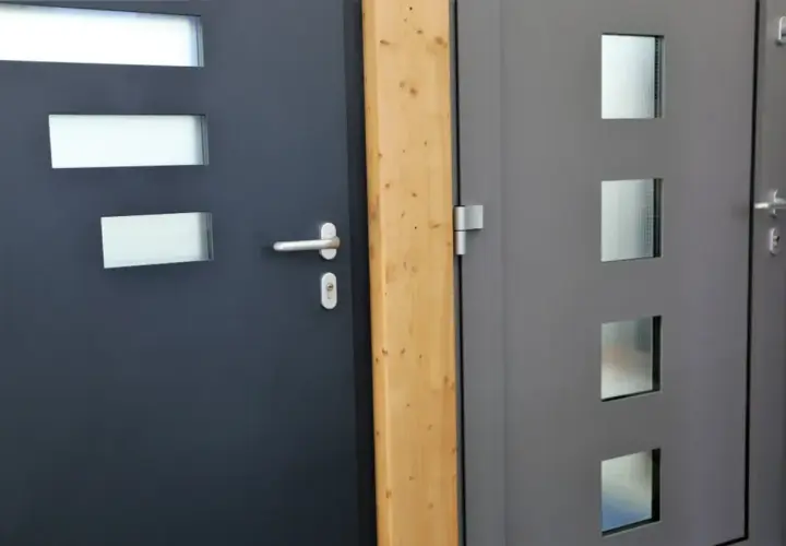 Dwa nowoczesne drzwi wejściowe, ciemnoszare i szare, z przeszkleniami. Dowiedz się, jak uszczelnić drzwi wejściowe, by chronić dom.