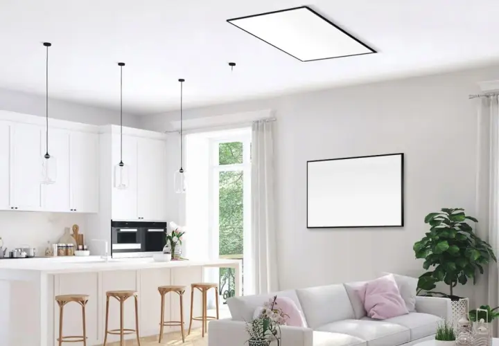 Nowoczesna kuchnia i salon z dyskretnym ogrzewaniem sufitowym wodnym. Białe meble, wyspa kuchenna, wygodna sofa i duży obraz na ścianie.