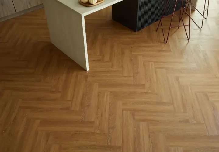 Drewnopodobne panele winylowe ułożone we wzór jodełki. Pokazują, jak układać panele winylowe, tworząc elegancką podłogę w kuchni.