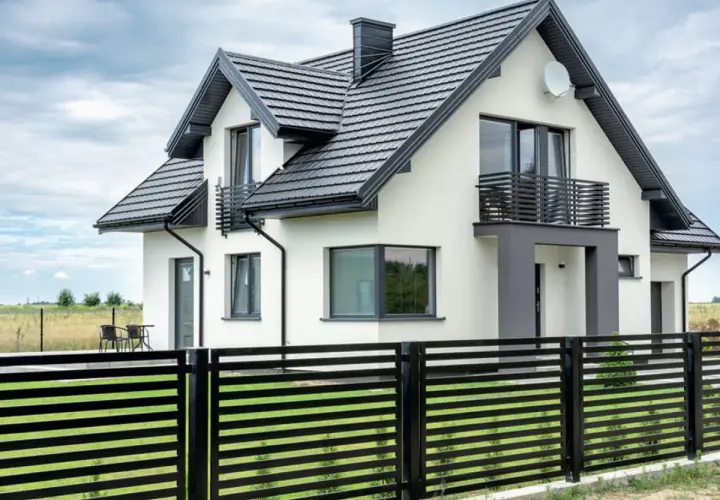 Nowoczesny dom z białymi ścianami i czarnym dachem. Eleganckie wykończenie ściany szczytowej podkreśla jego architekturę.