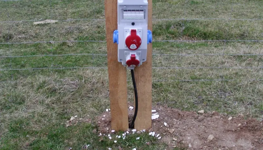 Skrzynka elektryczna na działce, gotowa do podłączenia narzędzi. Co dalej? Zasilanie dla Twoich projektów ogrodowych.