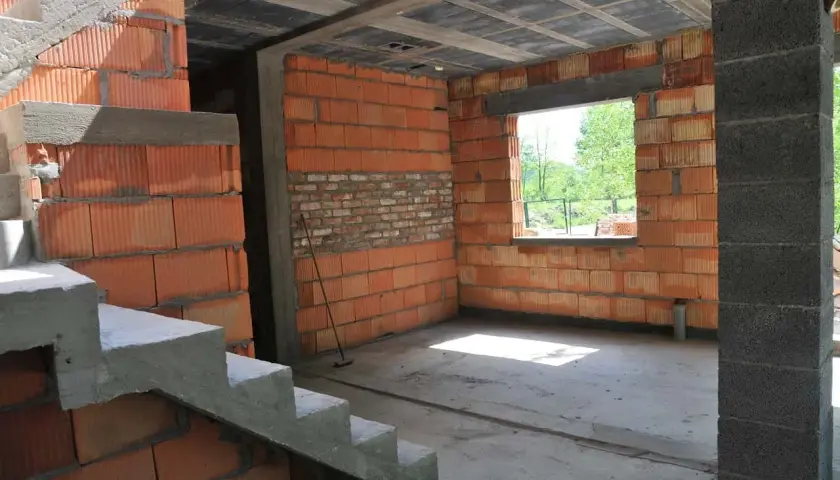 Trwa przekształcenie budynku gospodarczego na mieszkalny. Widoczne schody, ściany z pustaków ceramicznych i betonowy słup.