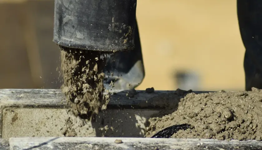 Beton wylewany z czarnej rury. Zastanawiasz się, ile schnie beton w temperaturze 5 stopni? Czekamy na odpowiedź.