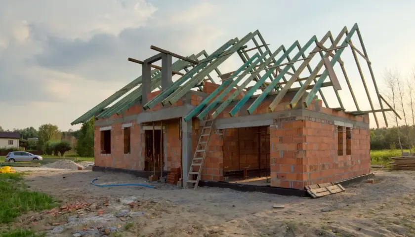 Budowa garażu bez pozwolenia 70m2. Dom w stanie surowym, z widoczną konstrukcją dachu.