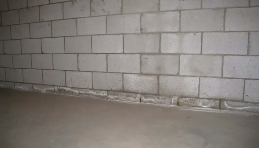 Ściana z bloczków betonowych, gdzie zaprawa murarska do bloczków betonowych tworzy solidne połączenie. Podłoga betonowa.