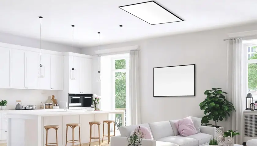 Nowoczesna kuchnia i salon z dyskretnym ogrzewaniem sufitowym wodnym. Białe meble, wyspa kuchenna, wygodna sofa i duży obraz na ścianie.