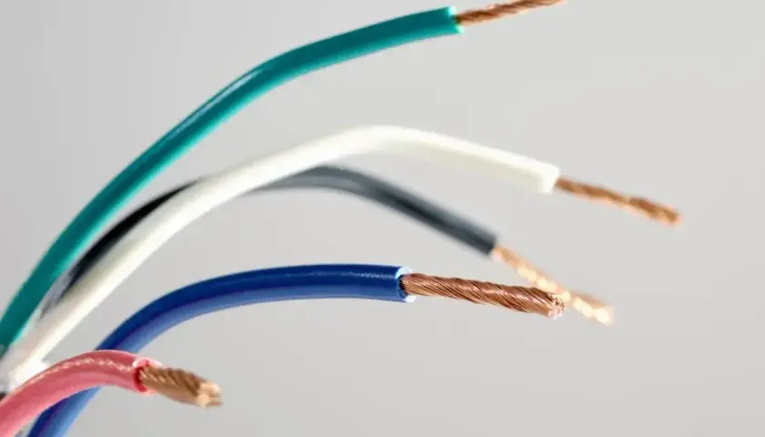 Kolorowe przewody elektryczne, każdy z odsłoniętym miedzianym rdzeniem. Widać oznaczenie prądu L na niebieskim kablu.
