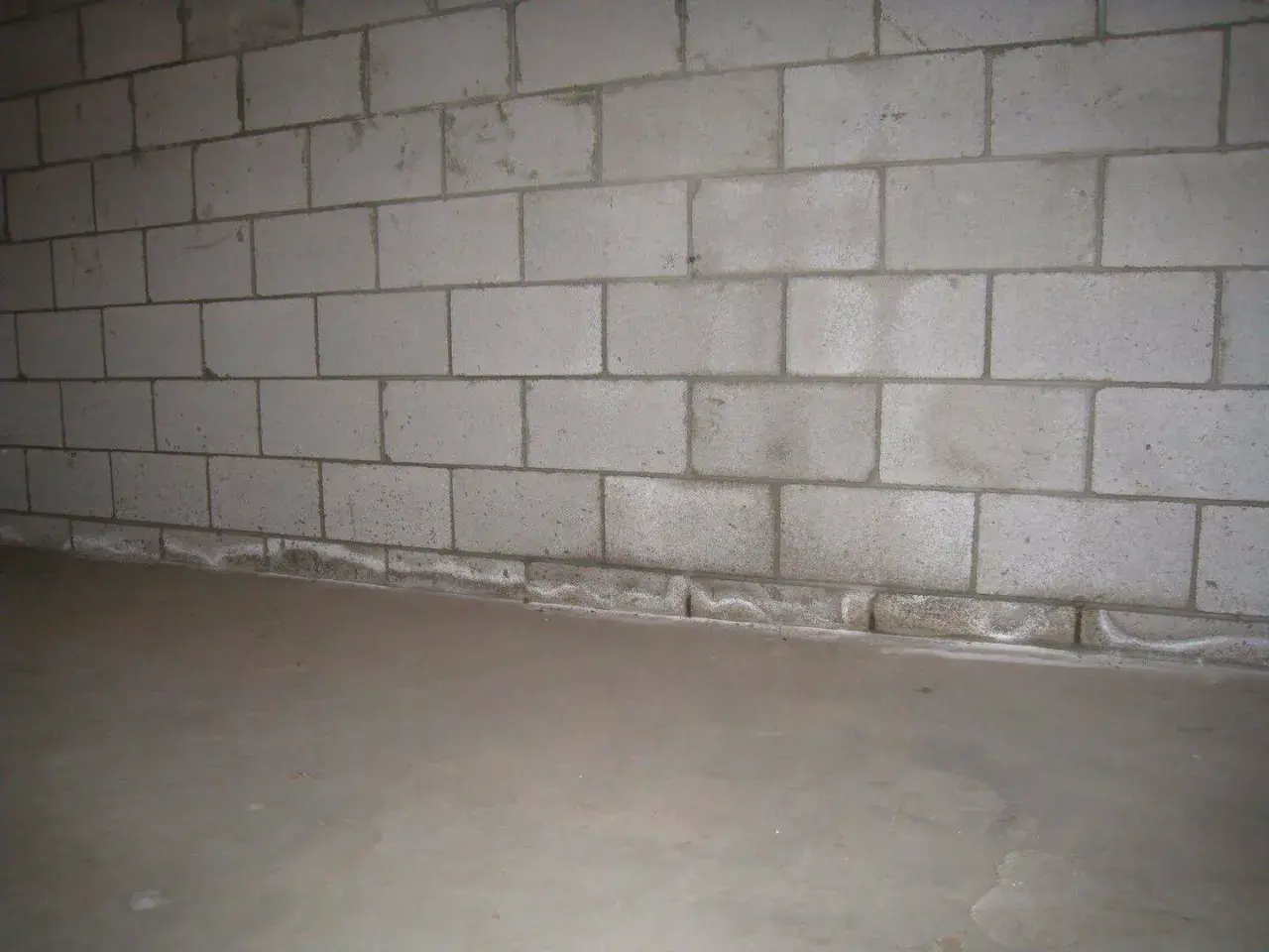Ściana z bloczków betonowych, gdzie zaprawa murarska do bloczków betonowych tworzy solidne połączenie. Podłoga betonowa.