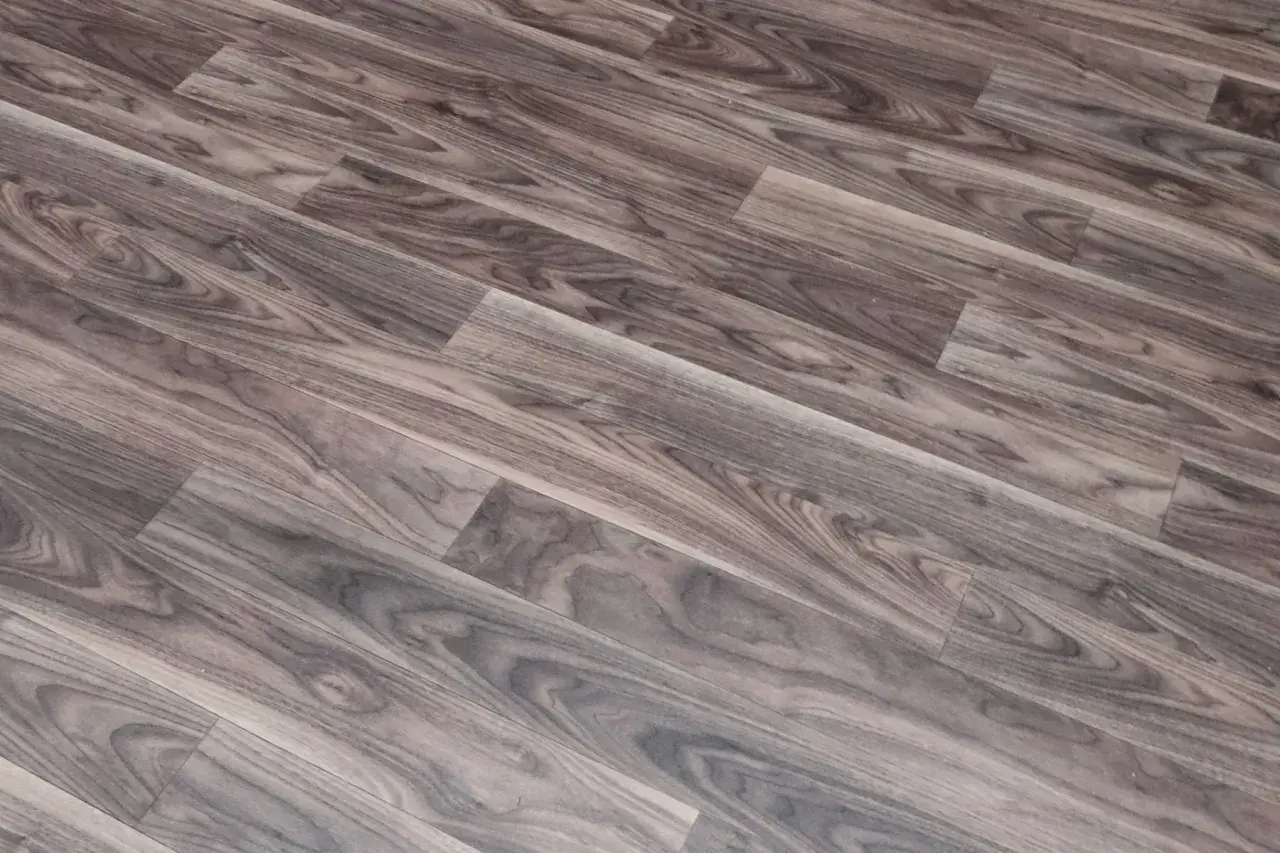 Szare linoleum na balkon, imitujące drewno, z widocznym usłojeniem. Idealne do stworzenia przytulnej przestrzeni.