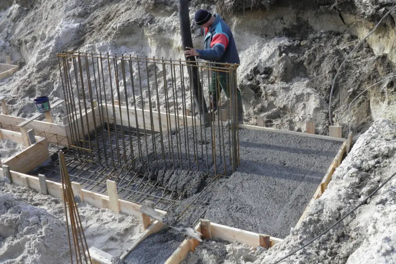 Pracownik wylewa beton do szalunku zbrojeniowego. W niskiej temperaturze, ok. 5 stopni, beton schnie dłużej.