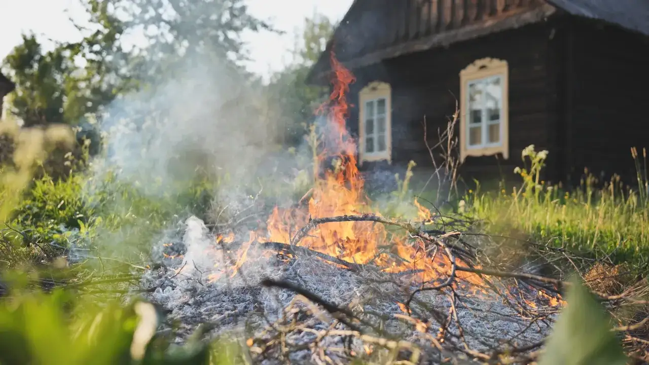 Ognisko z gałęzi płonie na wsi, unosząc dym. Czy można palić gałęzie na wsi? Tak, ale z rozwagą.