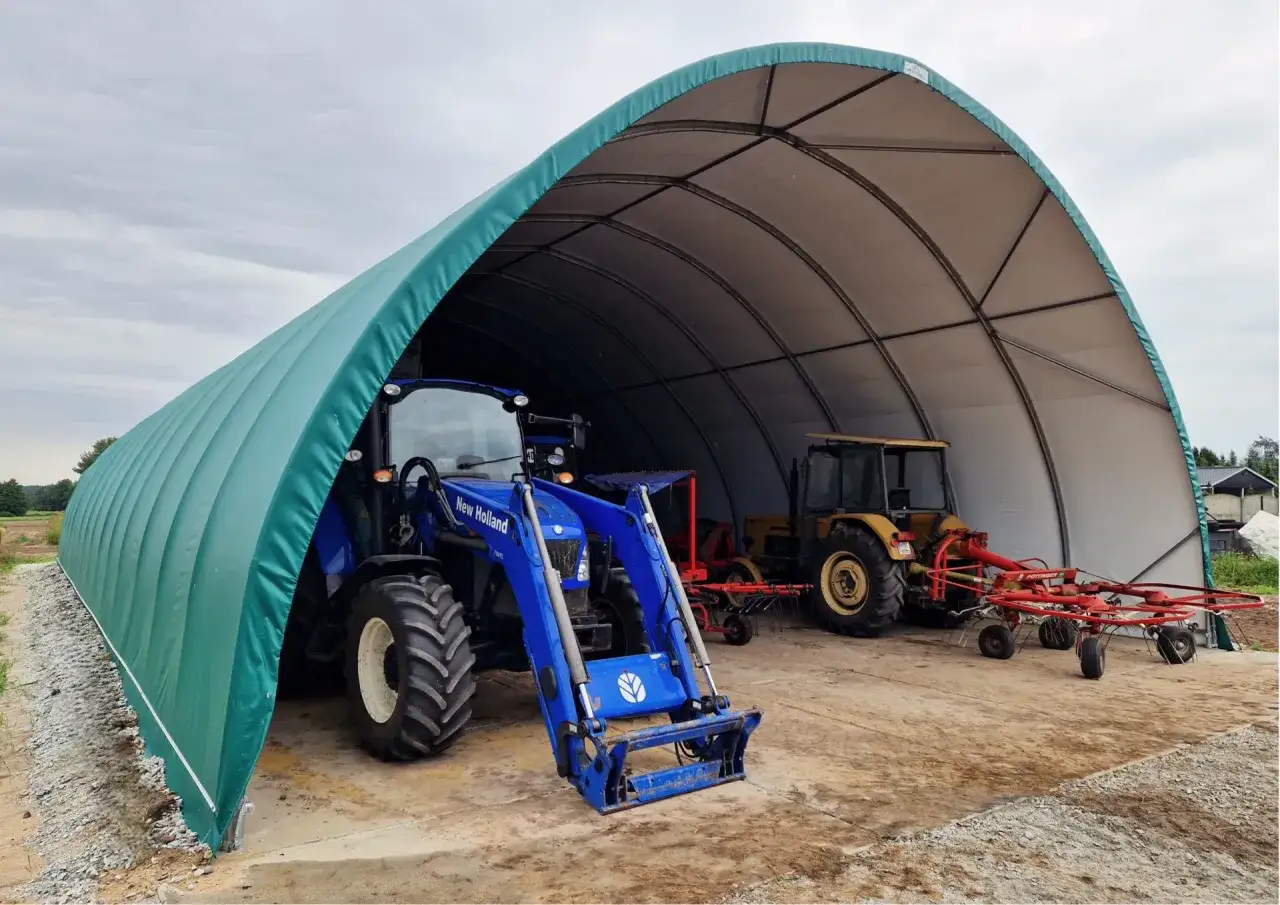 Niebieski traktor i żółty traktor stoją pod zieloną wiatą bez zgłoszenia. W tle widać maszyny rolnicze.
