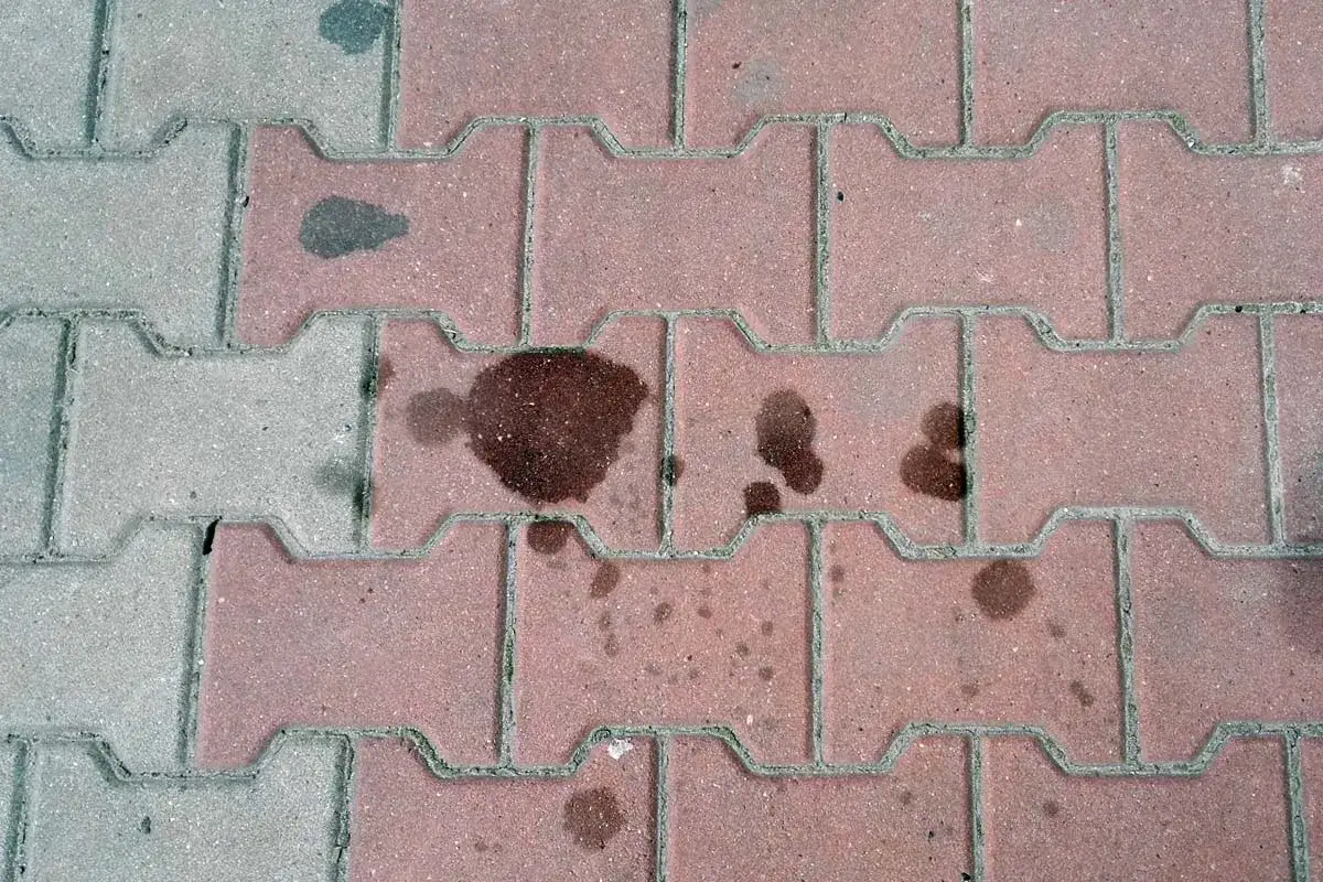 Stare plamy z oleju na kostce brukowej, świadczące o dawnych wyciekach z pojazdów.