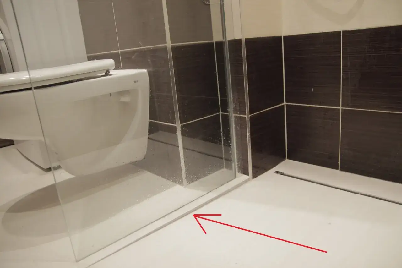 Widoczny spadek rury odpływowej WC w łazience, prowadzący do odpływu liniowego.